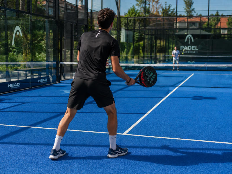 Hráč v plném výšvihu při hře padel – pohled ze strany kurtu, Padel Kuřim